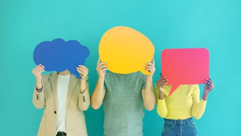 3 giovani si coprono il volto reggendo fumetti di carta colorata