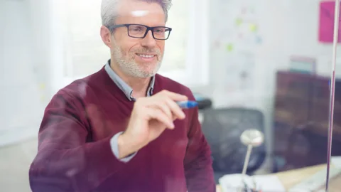 docente che scrive su parete di vetro